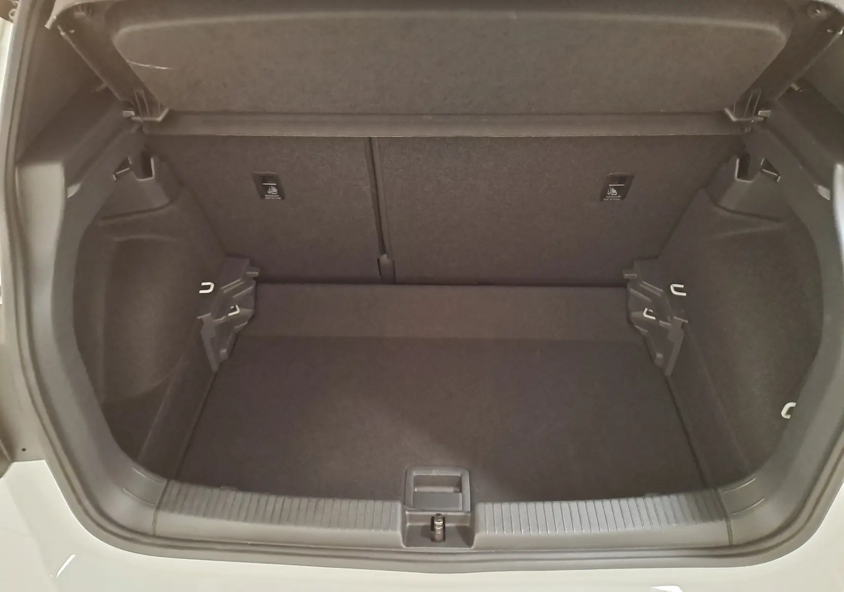 Coffre ouvert du Volkswagen T-Cross blanc pur 2025, vue de l'arrière montrant un espace de rangement propre et spacieux.