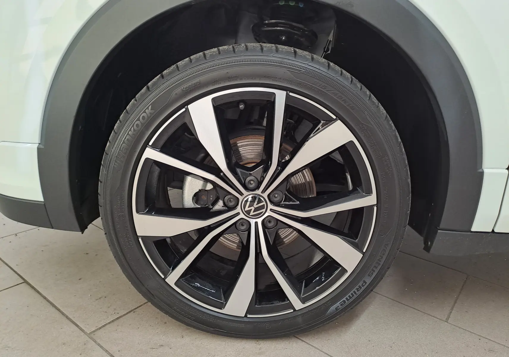 Gros plan sur la roue avant droite du Volkswagen T-Cross blanc Pur 2025 avec jante alliage R-Line bicolore.