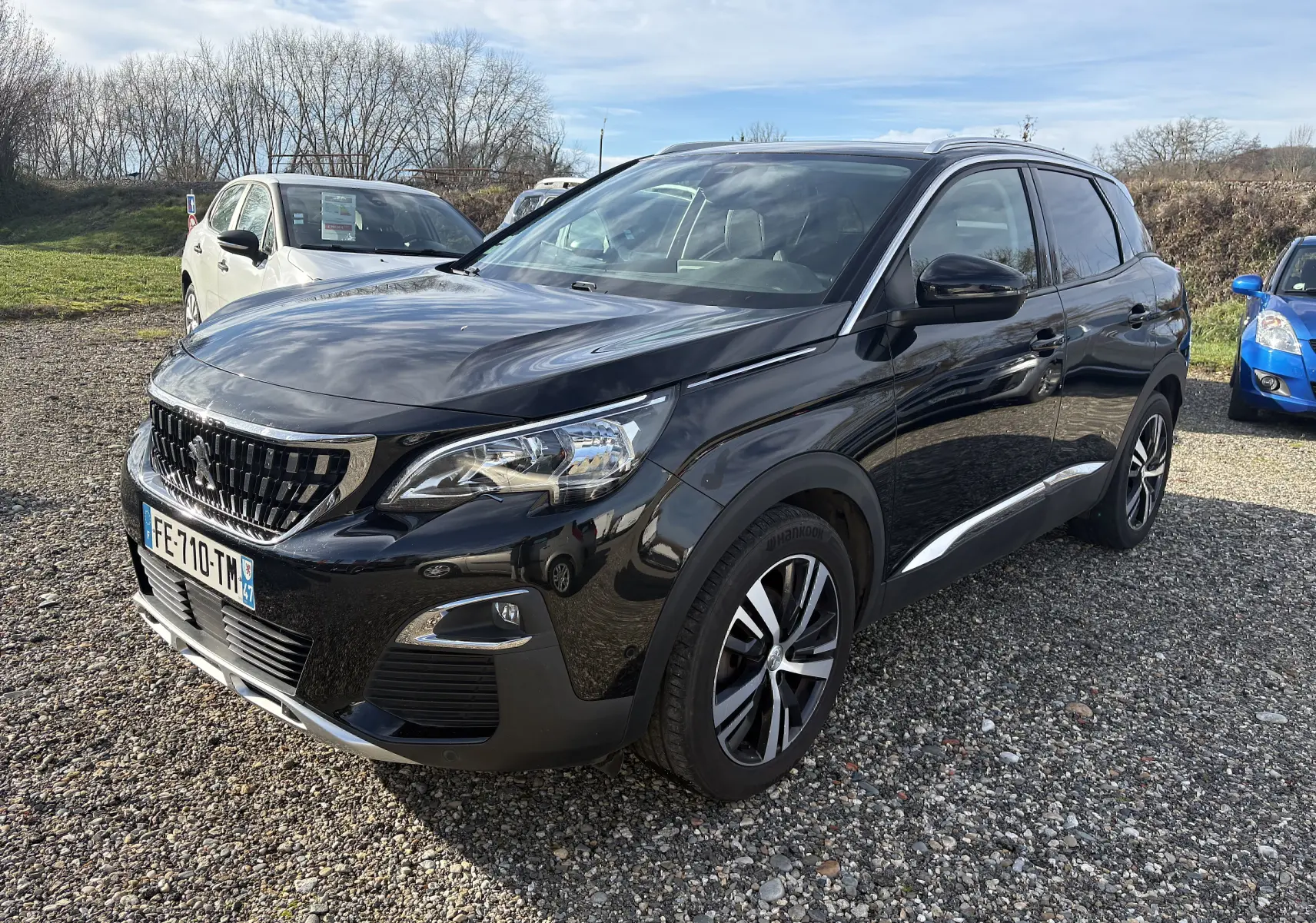 Peugeot 3008 noir vue 3/4 avant droit, avec jantes alliage et calandre chromée brillante, stationné sur gravier.