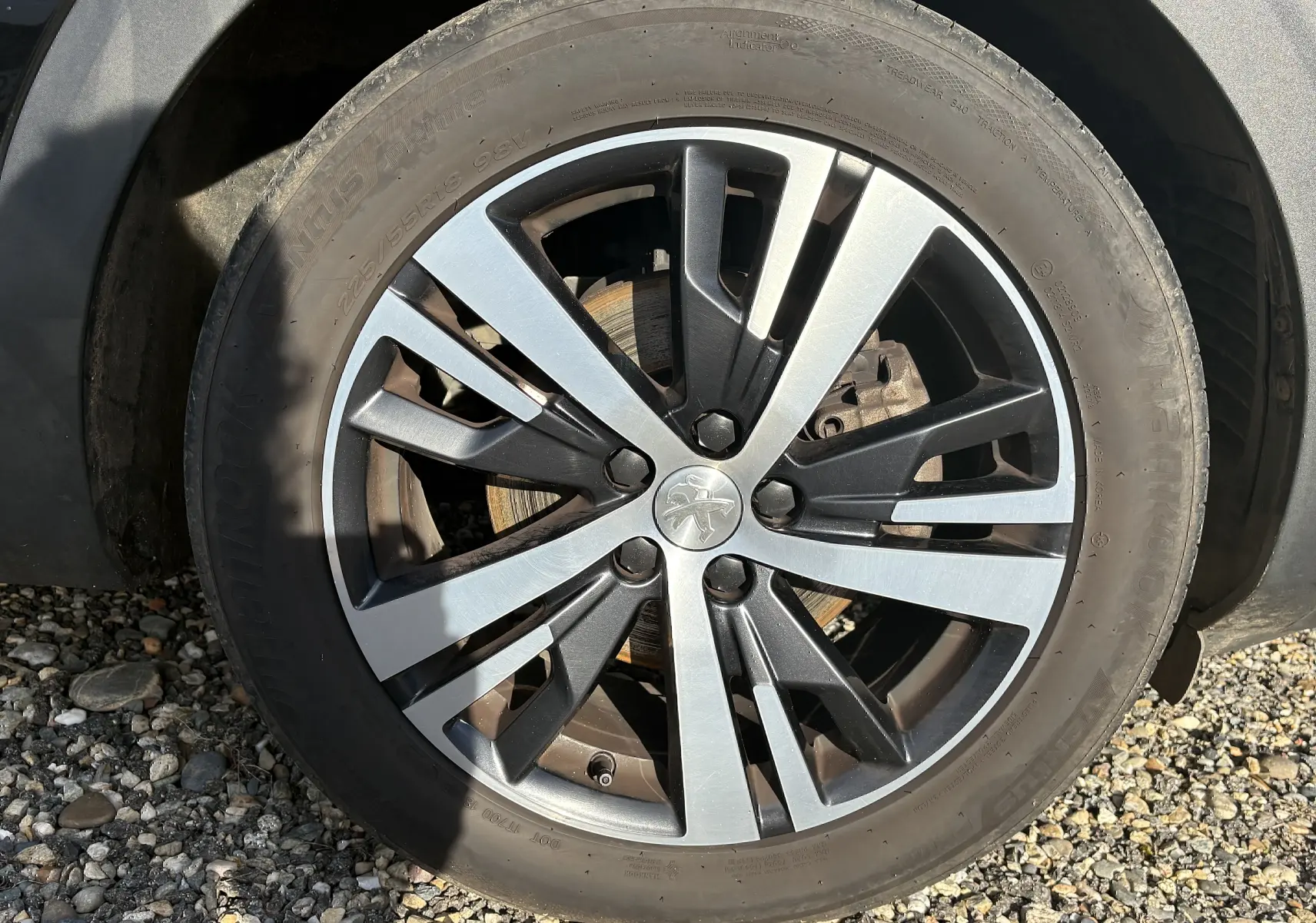 Gros plan sur la roue avant gauche du Peugeot 3008 II 1.5 BlueHDi 130 Active avec jante alliage bicolore.