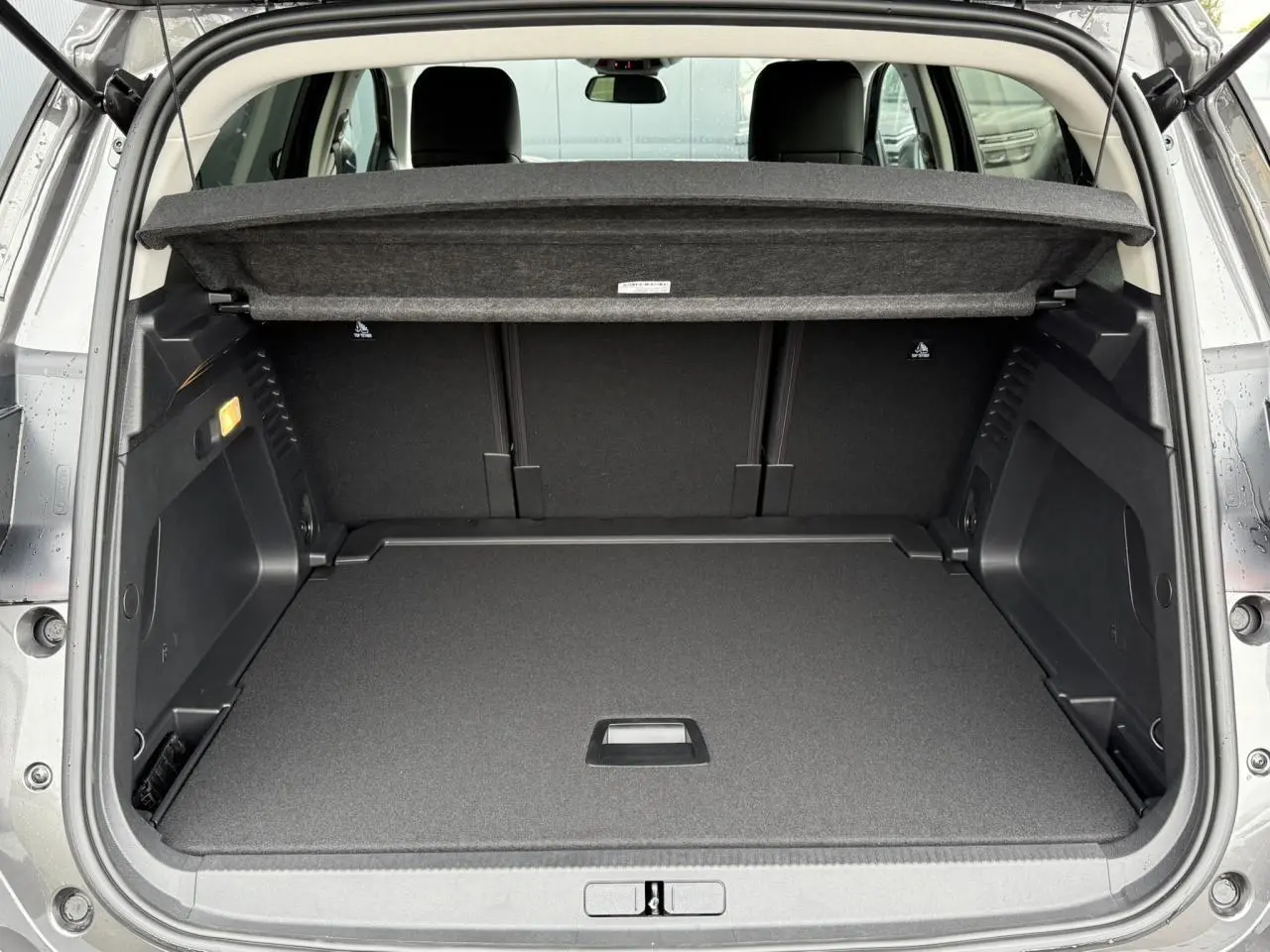 Coffre ouvert vu de l'arrière du Citroën C5 Aircross gris Platinium, montrant un espace de chargement propre et modulable.