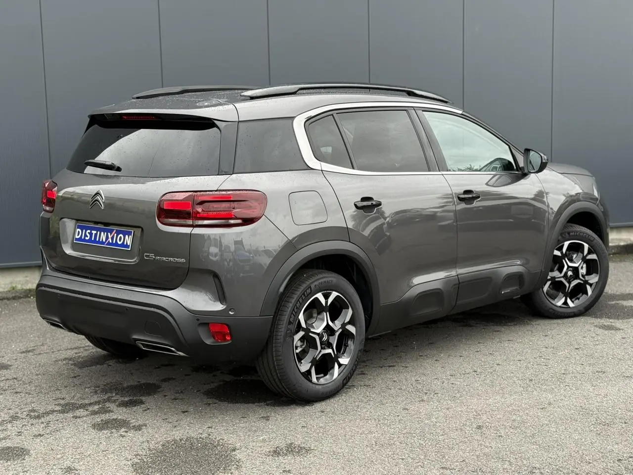 Vue 3/4 arrière droite d'un Citroën C5 Aircross gris Platinium avec toit noir et jantes bi-ton 18 pouces.