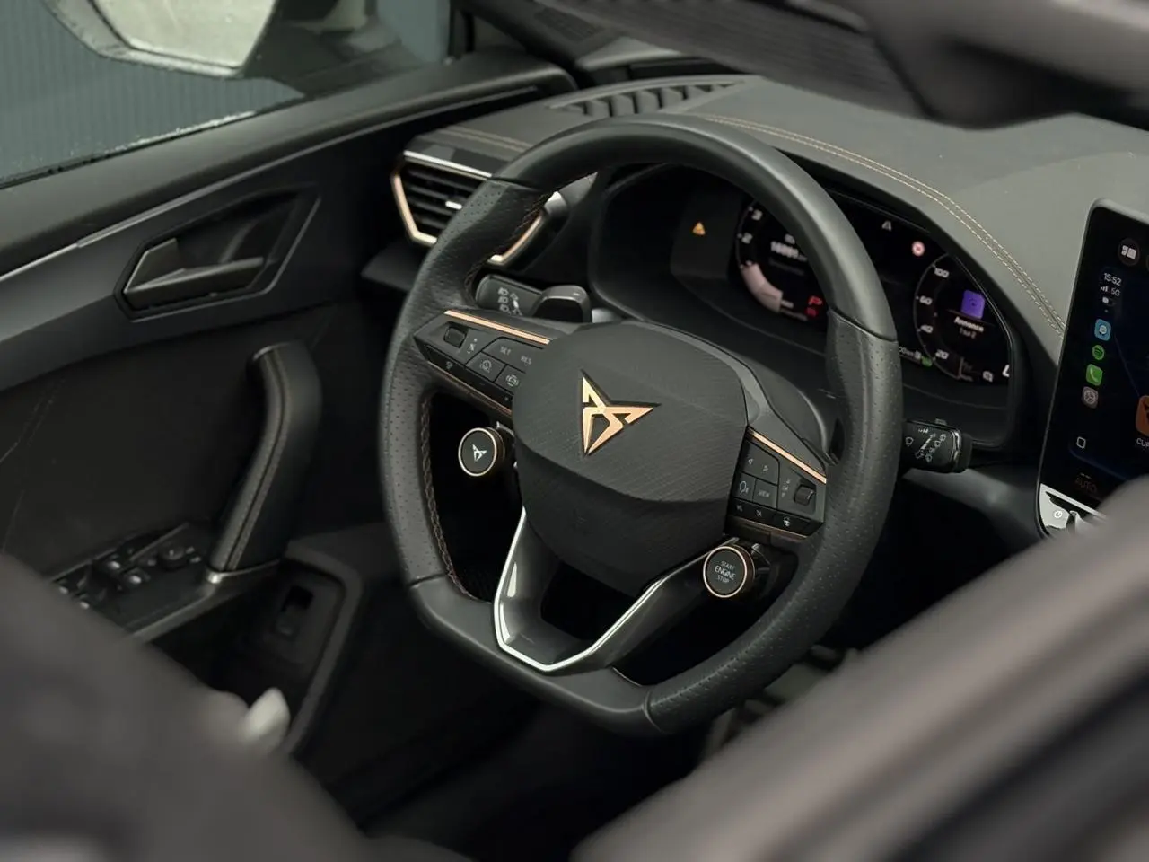 Vue rapprochée du volant CUPRA noir avec logo cuivré et tableau de bord numérique du Leon ST 2025.