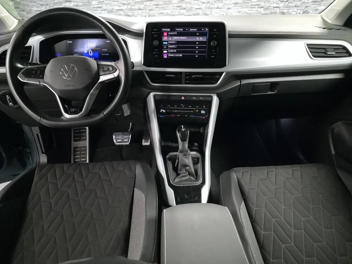 Vue intérieure frontale du Volkswagen T-Roc 2025 avec tableau de bord gris étain et écran tactile central.
