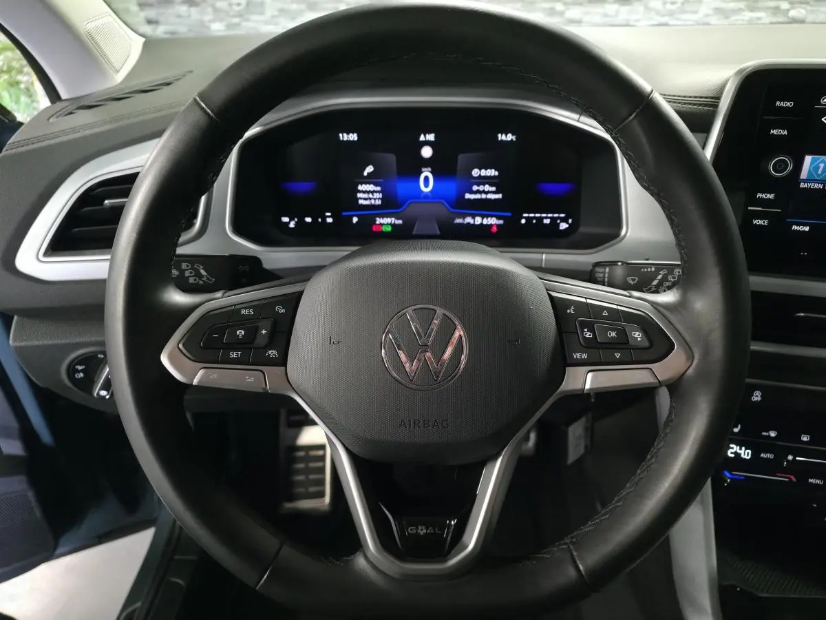 Volant en cuir noir avec logo Volkswagen, vue frontale sur le tableau de bord digital du T-Roc bleu 2025.