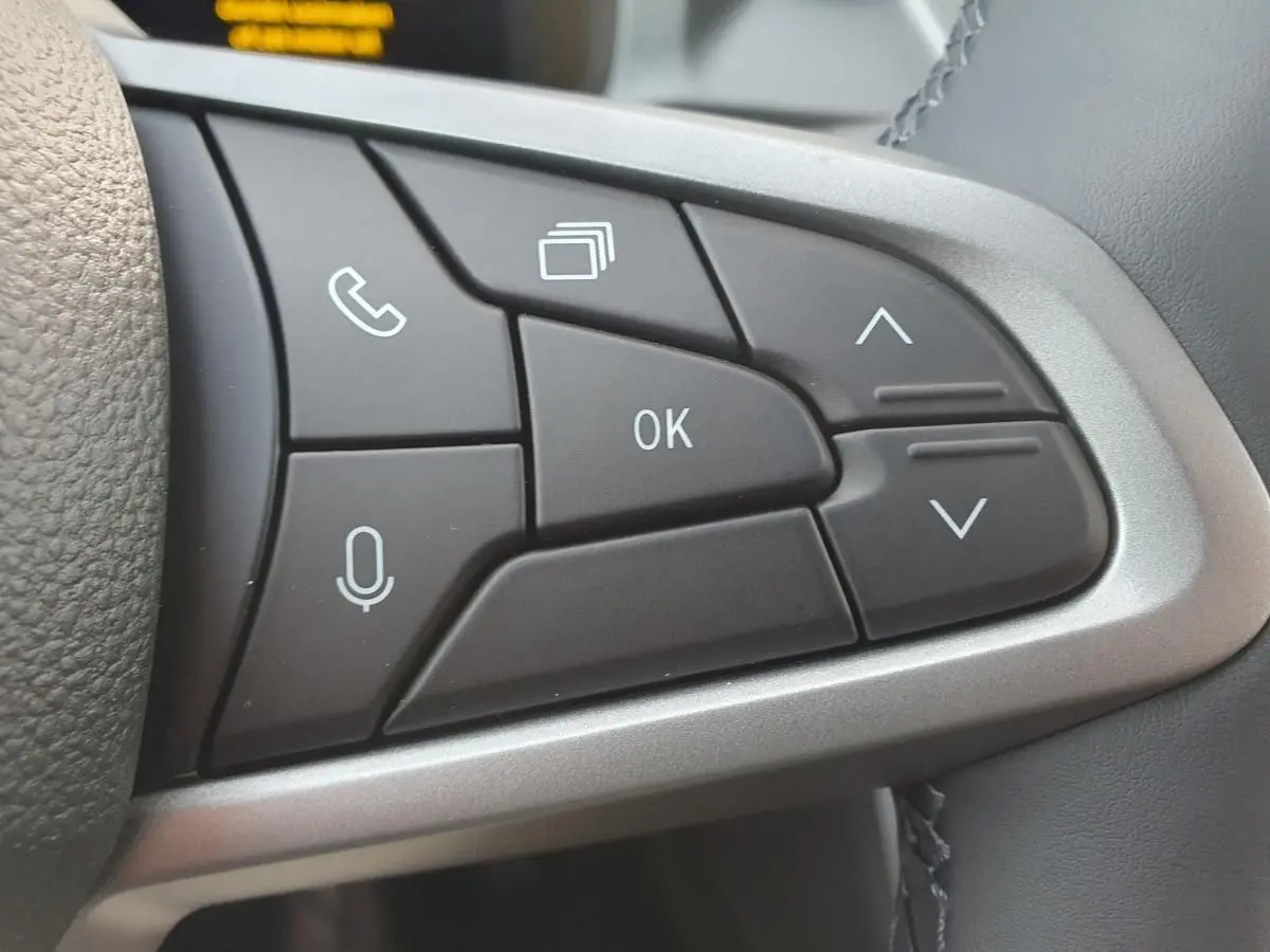 Gros plan sur les commandes multifonctions au volant du Dacia Bigster 2026, boutons noirs avec icônes blanches.