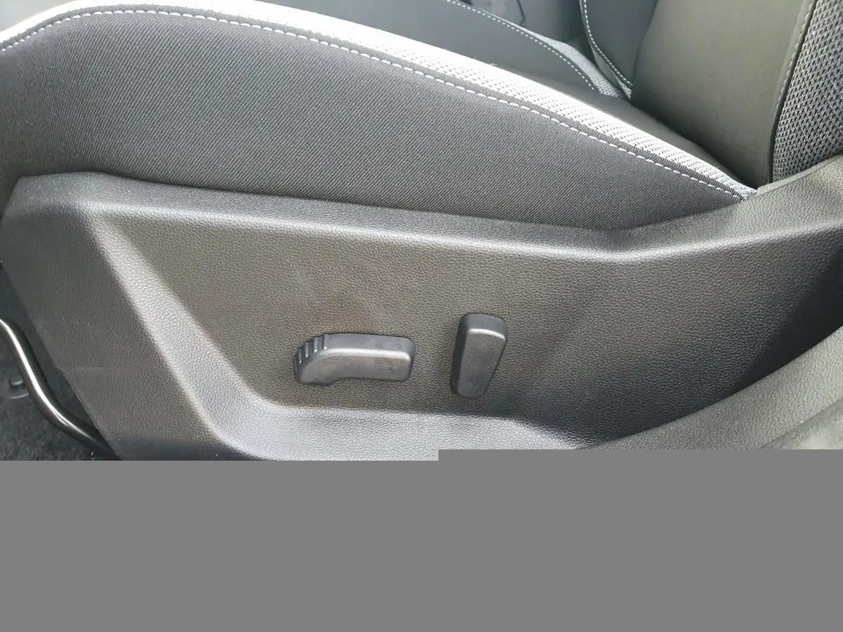 Gros plan sur les commandes de réglage lombaire du siège conducteur du Dacia Bigster noir Perla, intérieur tissu gris.