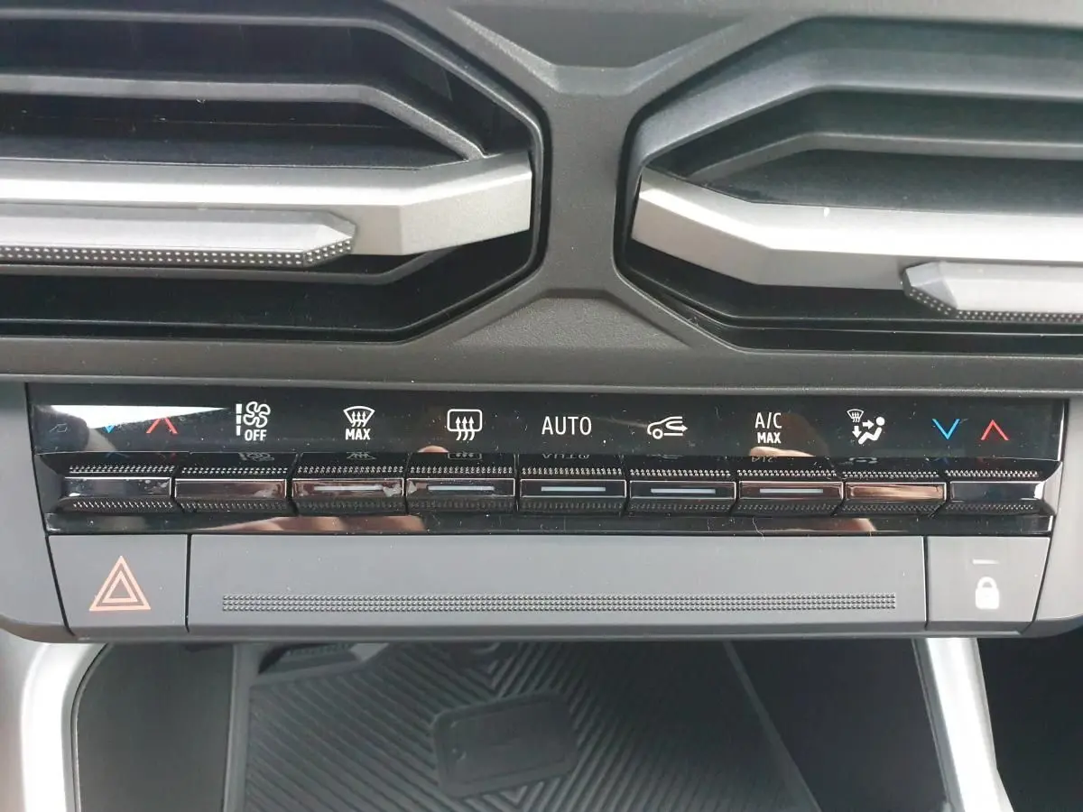 Vue rapprochée du tableau de bord de la Dacia Bigster 2026, montrant les commandes de climatisation automatique et les aérateurs noirs.