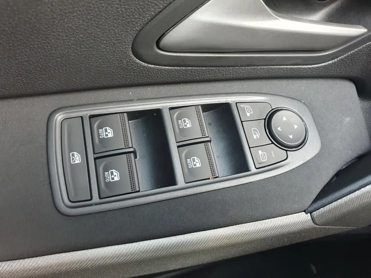Vue rapprochée des commandes de lève-vitres et rétroviseurs sur la porte côté conducteur d’un Dacia Bigster noir Perla.