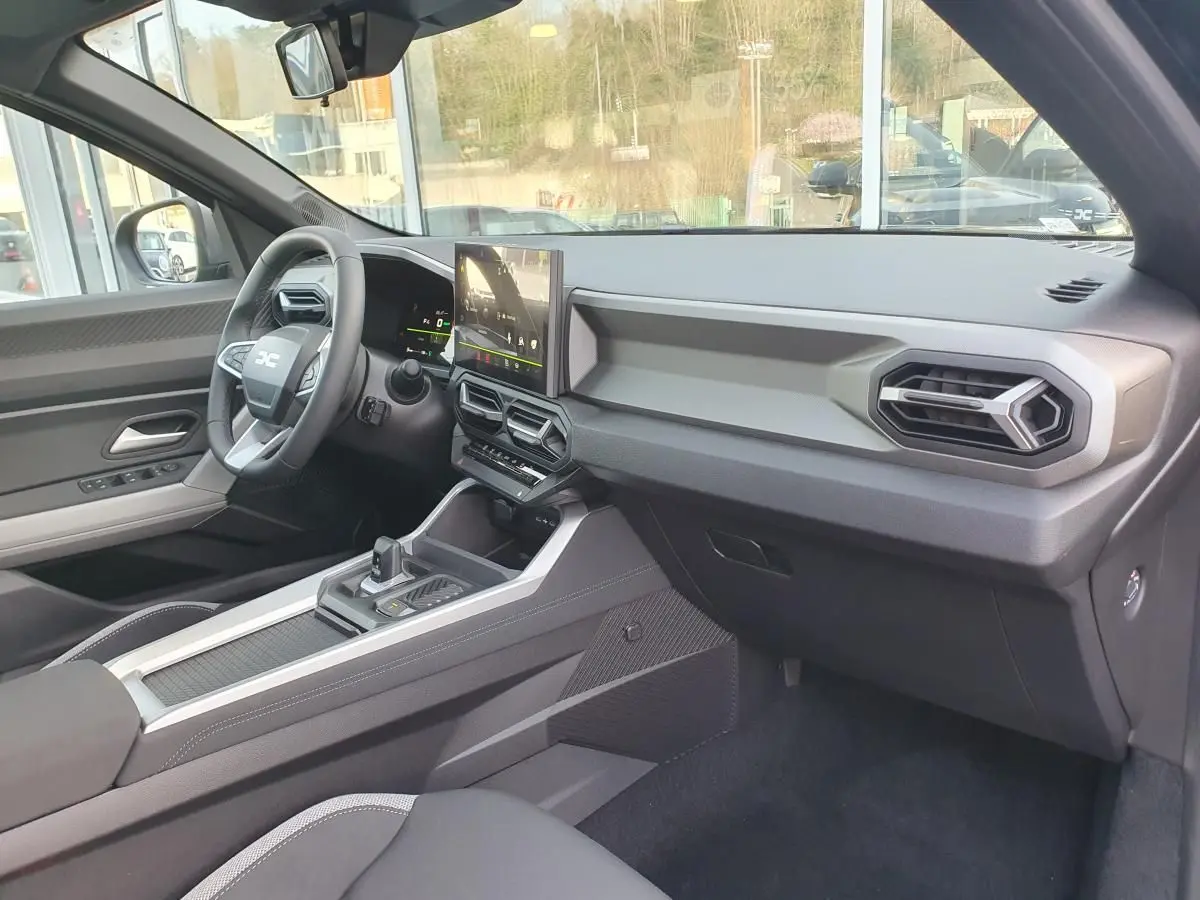 Intérieur du Dacia Bigster 2026 vu côté passager, tableau de bord moderne avec écran central tactile.