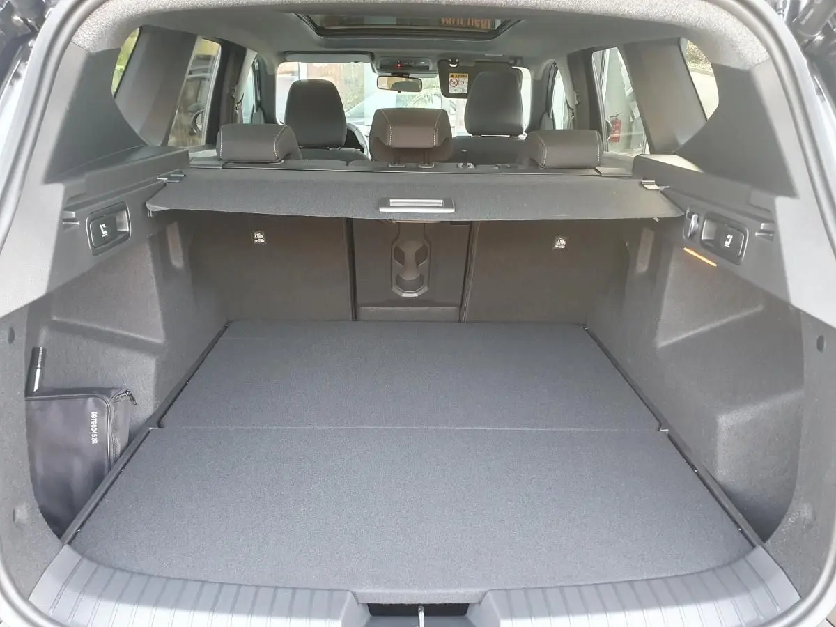 Vue arrière du coffre spacieux du Dacia Bigster noir Perla avec banquette rabattue et cache-bagages déployé.