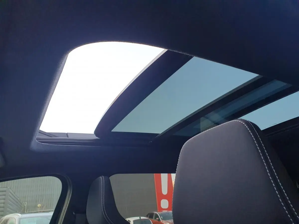 Vue intérieure du toit panoramique ouvert du Dacia Bigster noir Perla, avec appui-tête avant visible.