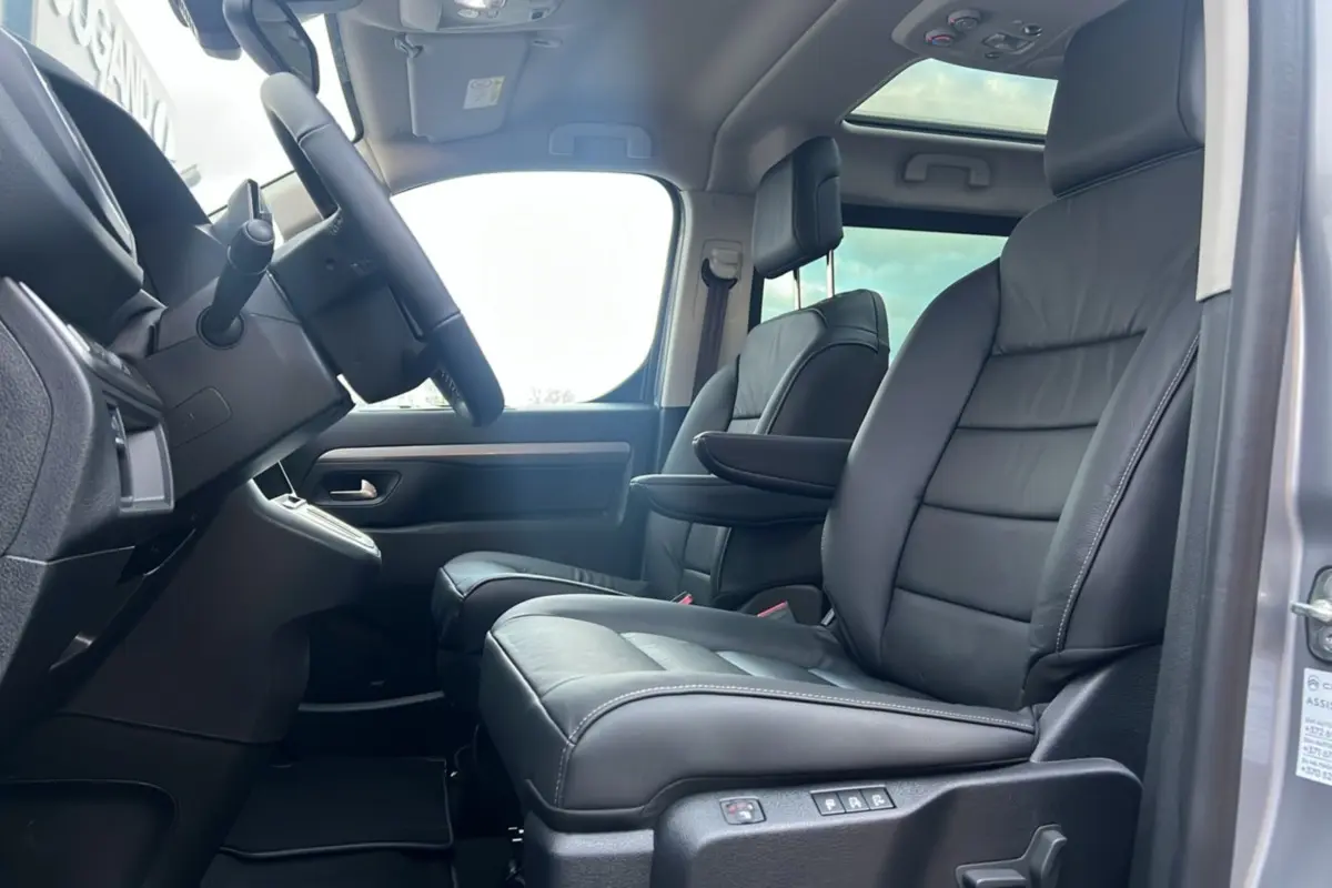 Vue intérieure côté conducteur du Citroën Spacetourer gris acier, sièges avant cuir noir avec accoudoir et toit panoramique.
