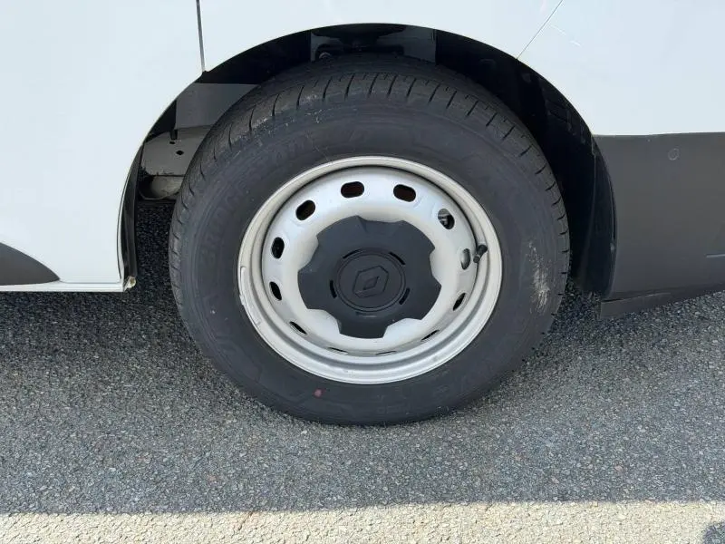 Gros plan sur la roue avant gauche blanche du Renault Trafic Fourgon L1H1 2024, avec jante acier et logo central noir.