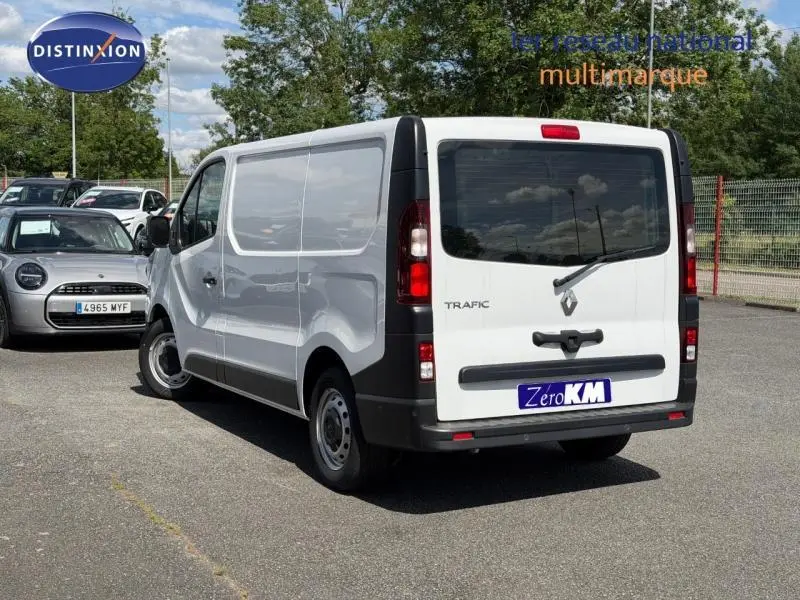 Vue 3/4 arrière droite d'un Renault Trafic Fourgon blanc Glacier avec portes arrière fermées sur parking extérieur.