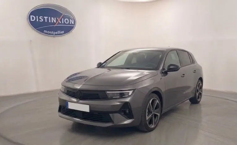 Opel Astra 2024 gris en 3/4 avant droit, avec calandre noire et jantes alliage distinctives, dans un studio lumineux.