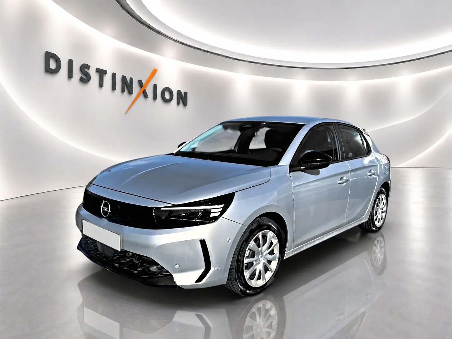 Opel Corsa gris 3/4 avant droit dans un showroom lumineux avec logo Distinxion en arrière-plan.