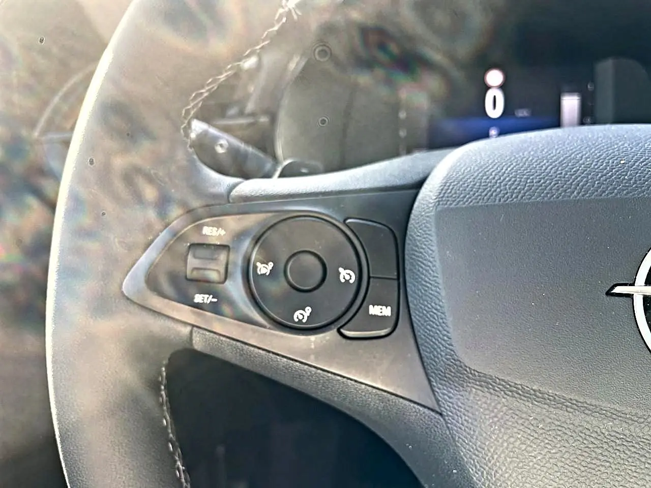 Gros plan sur la partie gauche du volant gris de l'Opel Corsa 2025 avec commandes multifonctions visibles.