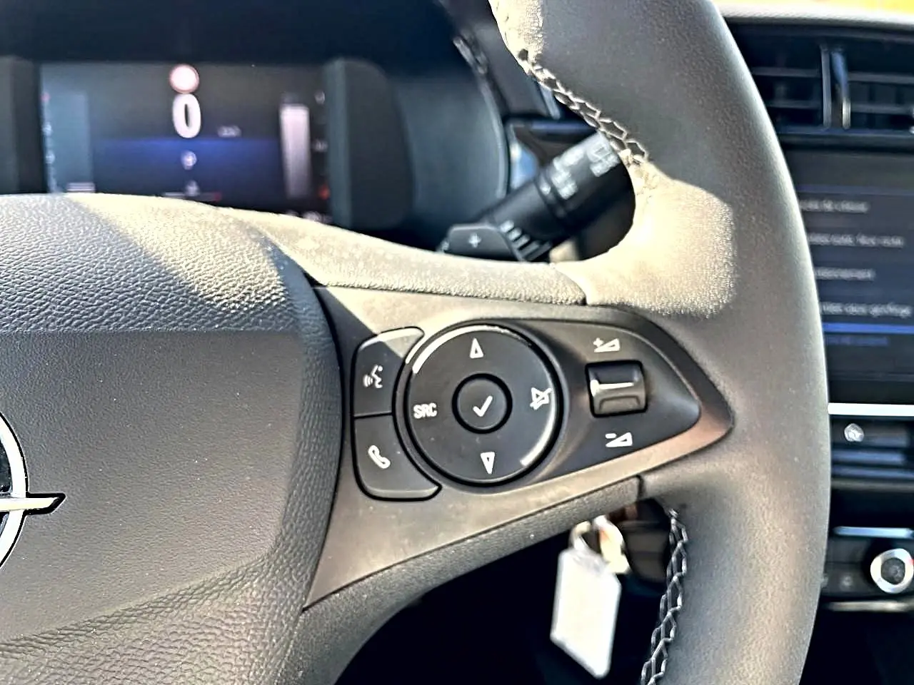 Gros plan sur le volant multifonction noir de l'Opel Corsa 2025 avec commandes audio et logo Opel visible.