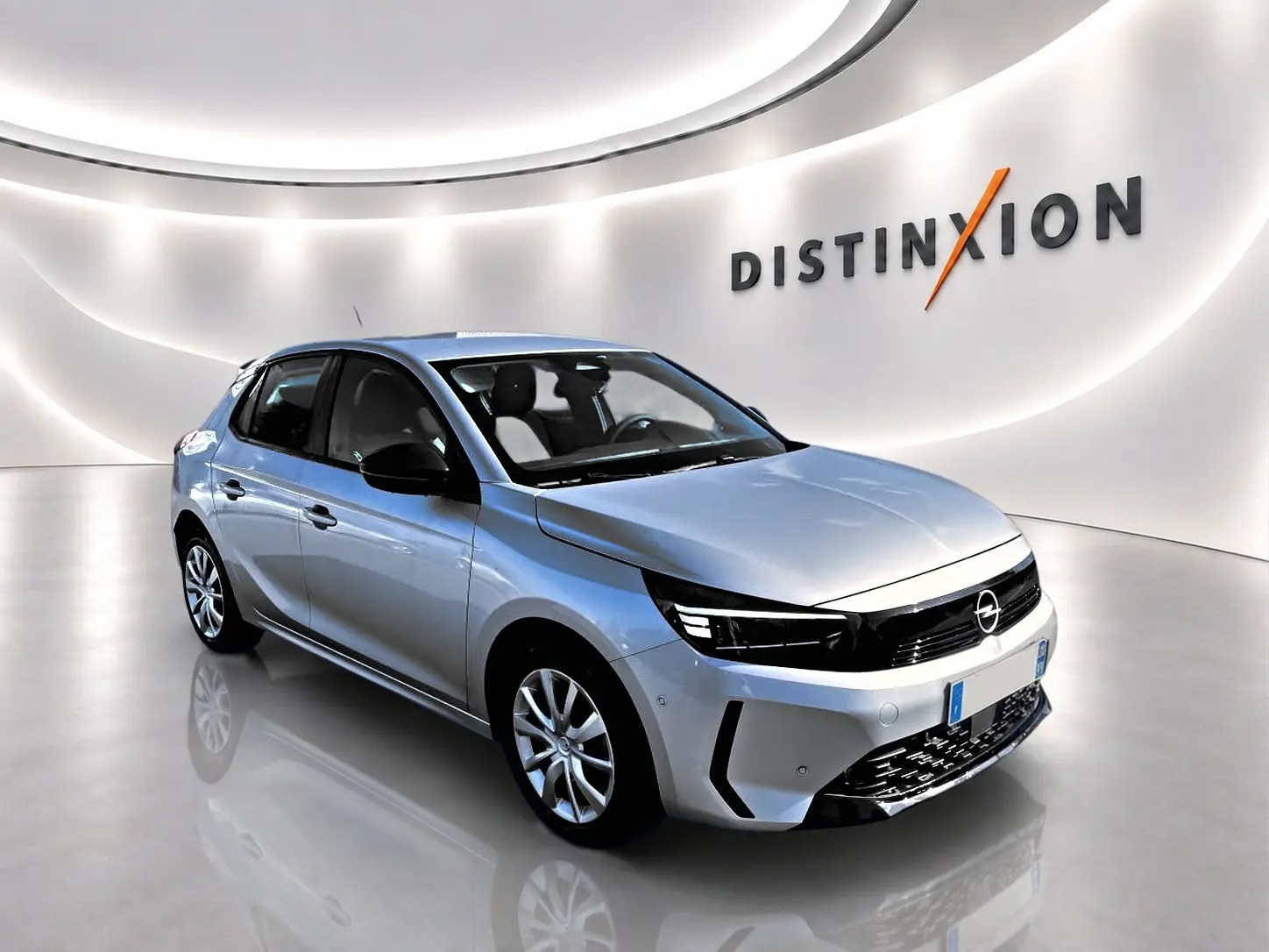 Opel Corsa gris en 3/4 avant droit dans un showroom lumineux avec calandre noire et jantes alliage.