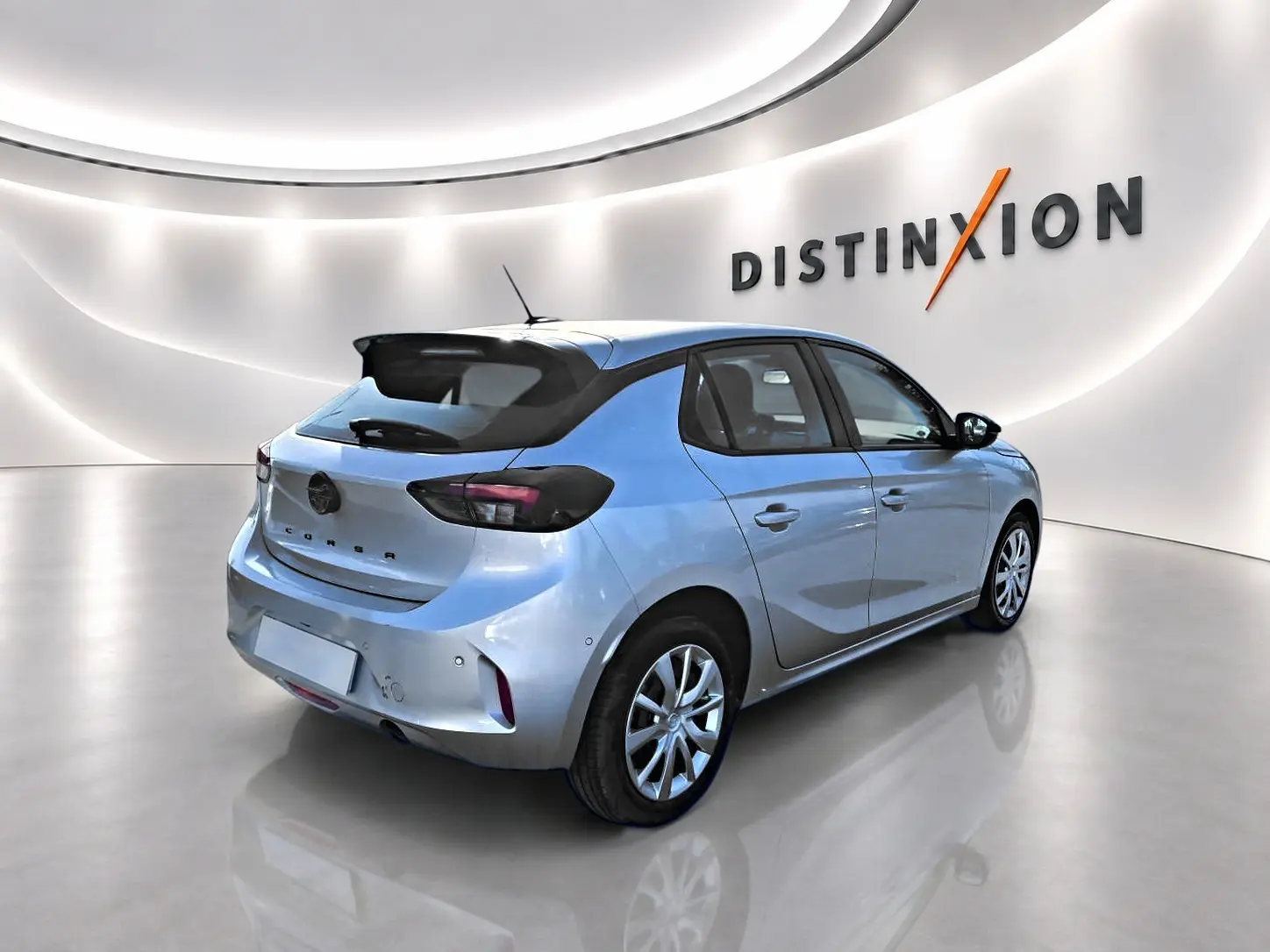 Opel Corsa gris vue 3/4 arrière droit en intérieur avec toit noir et becquet arrière distinctif.