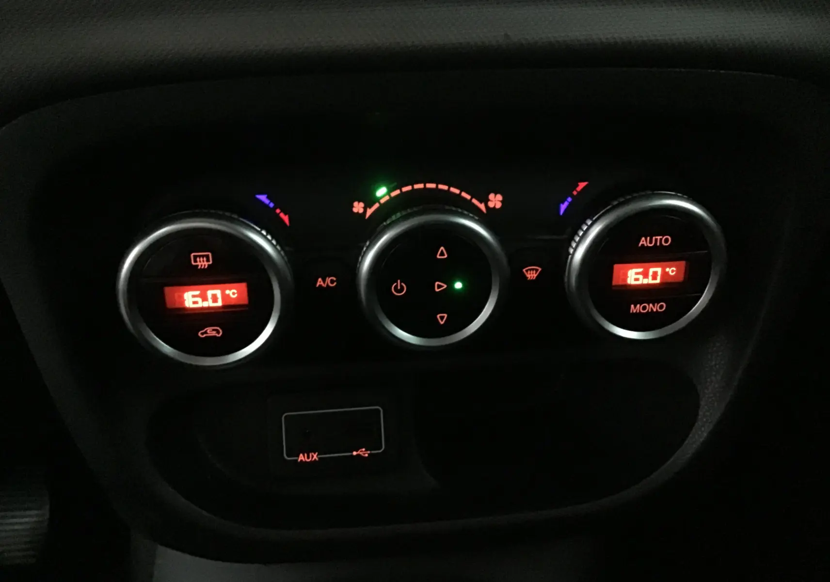 Gros plan sur les commandes de climatisation numérique rouge du tableau de bord d'une Fiat 500L blanche de 2015.