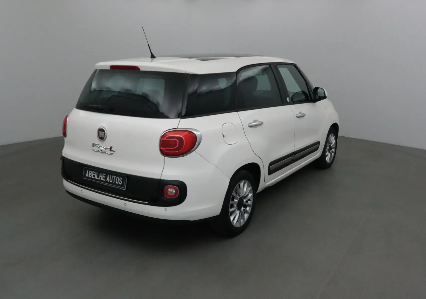 Fiat 500L blanc en 3/4 arrière droit, avec lunette arrière surteintée et jantes alliage 16 pouces.