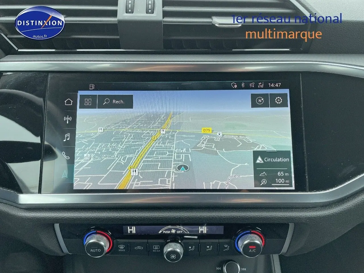 Vue rapprochée de l'écran tactile central et de la console de climatisation d'un Audi Q3 gris chronos métal de 2019.
