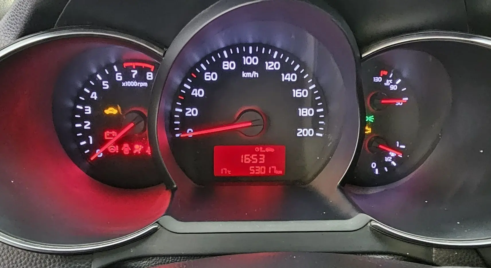 Tableau de bord de Kia Picanto 2016 avec compte-tours, compteur de vitesse et jauges éclairés en rouge et blanc.