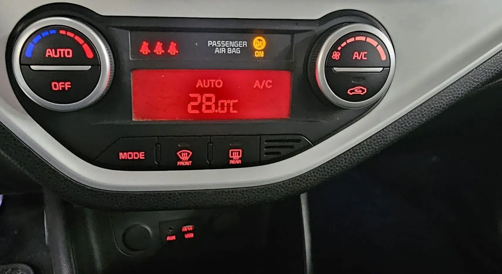 Détail du tableau de bord de la KIA PICANTO II 2016 montrant la climatisation automatique réglée à 28°C.