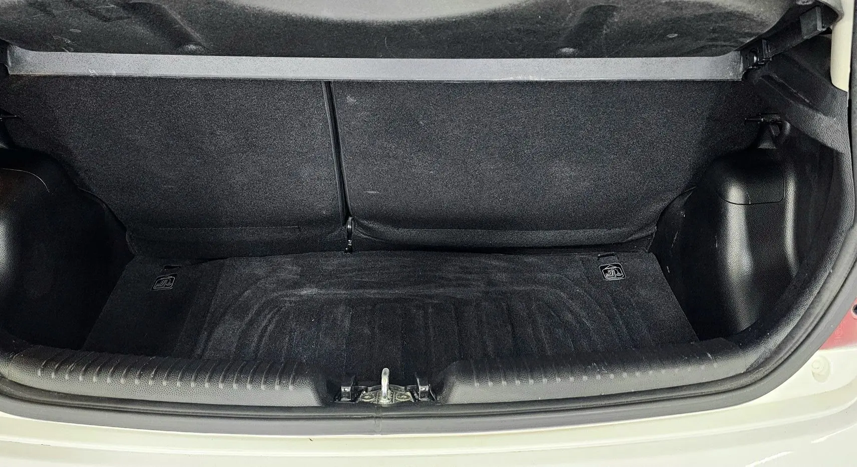 Coffre ouvert d'une KIA PICANTO II blanche de 2016, montrant l'espace de rangement intérieur propre et vide.