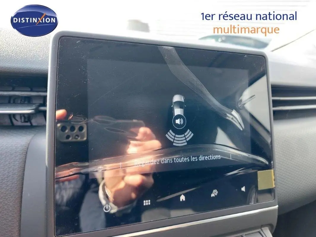 Écran tactile central du tableau de bord de la Renault Clio blanche 2021, affichant l'aide au stationnement.