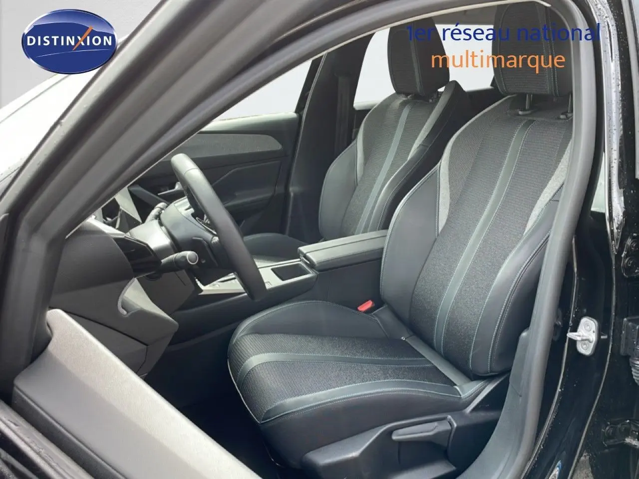 Vue intérieure côté conducteur de la Peugeot 308 SW Hybrid 145ch Allure 2025, sièges tissu et cuir noir métal.