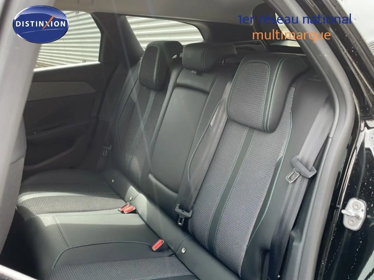 Vue intérieure arrière côté droit du Peugeot 308 SW Hybrid 2025 noir métal, sièges tissu et cuir avec surpiqûres contrastées.