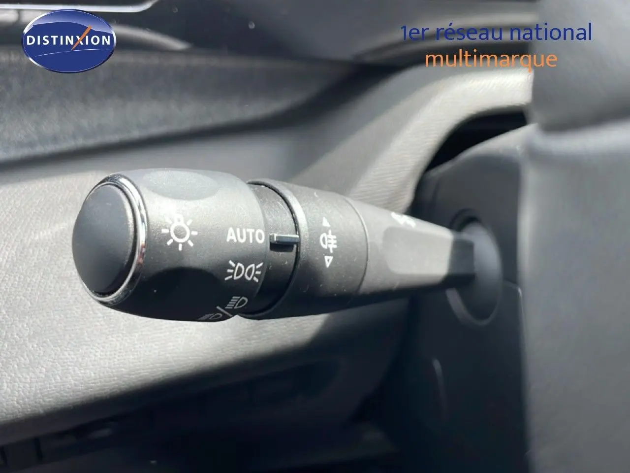 Gros plan sur la commande des phares en plastique noir dans l'habitacle d'une Peugeot 308 SW noir métal 2025.