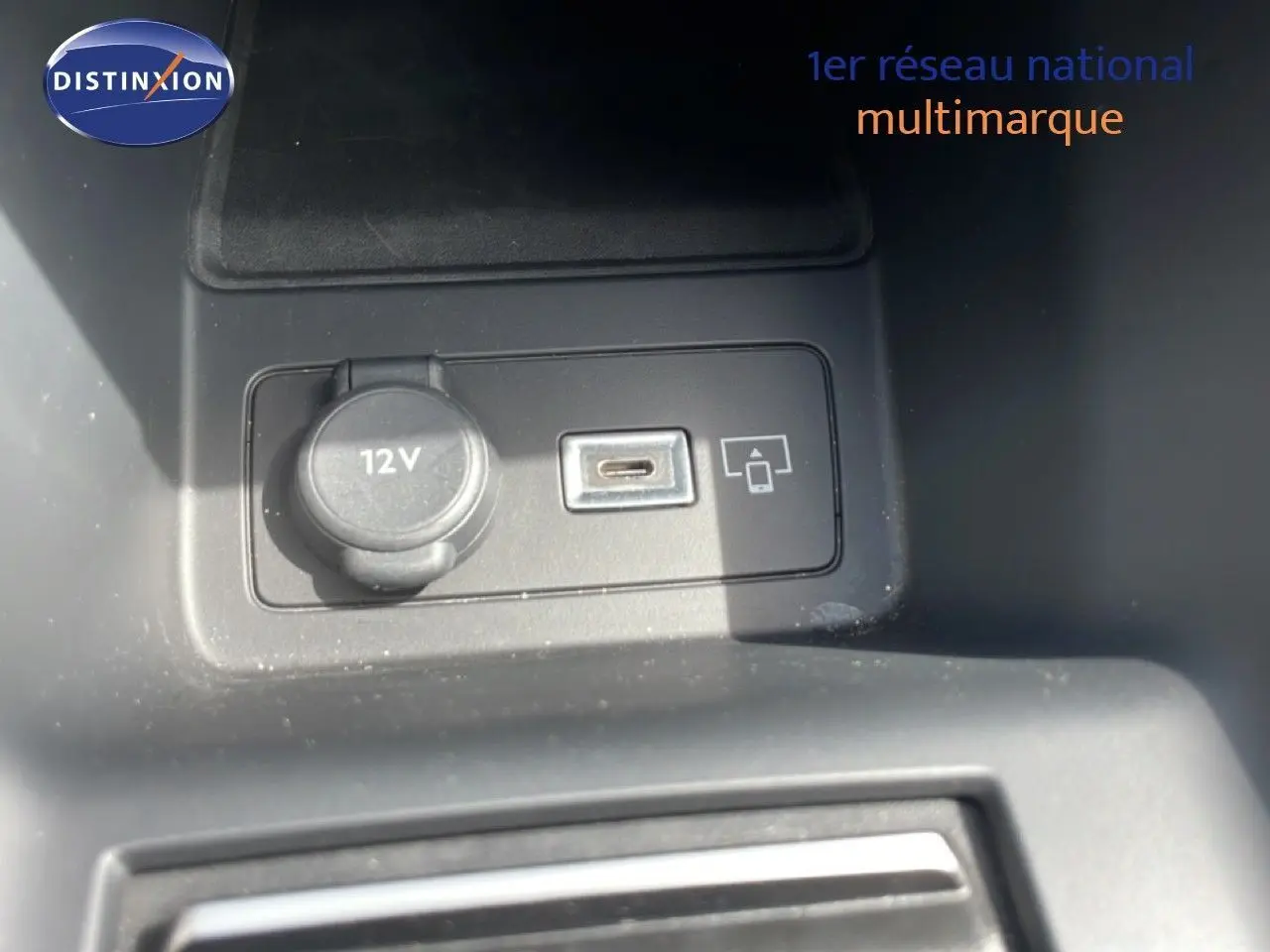 Vue rapprochée de la prise 12V et port USB dans l'habitacle noir d'une Peugeot 308 SW Hybrid 2025.