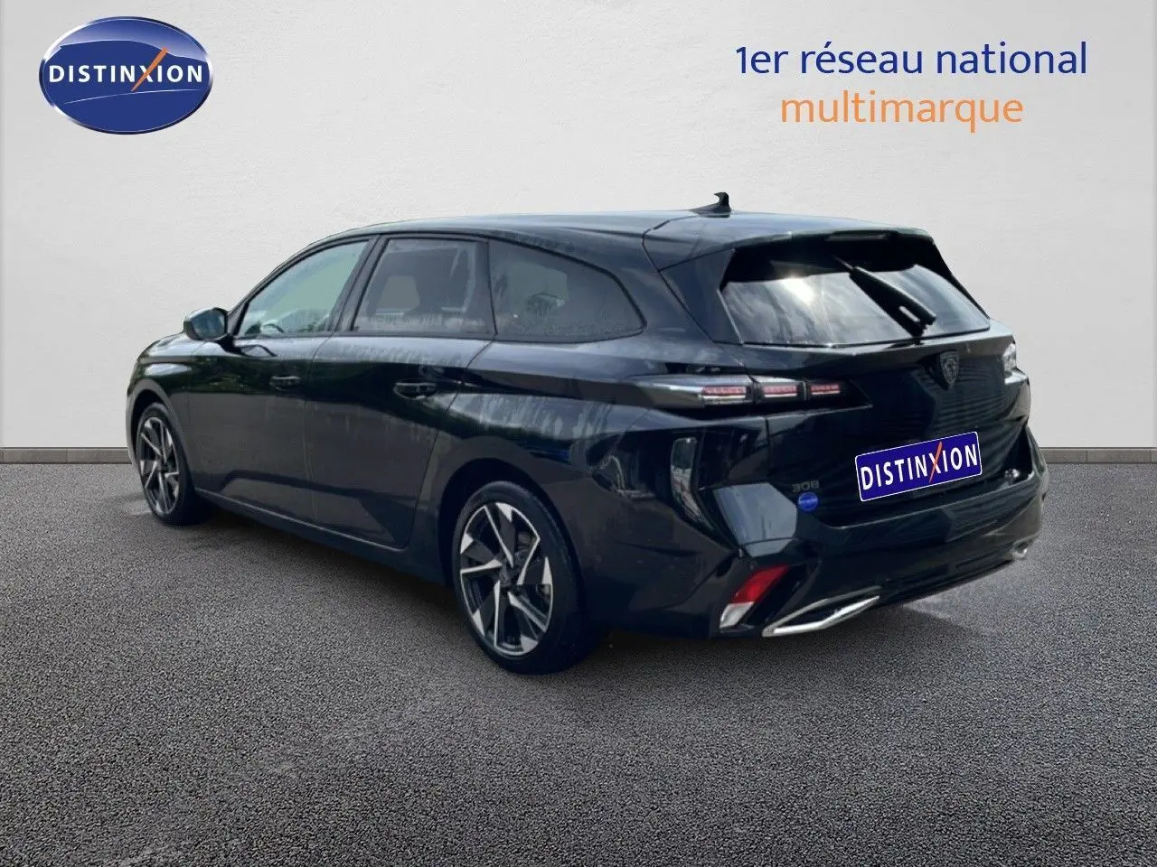 Vue 3/4 arrière droite d'une Peugeot 308 SW Hybrid noire métal avec jantes alliage et feux arrière LED distinctifs.