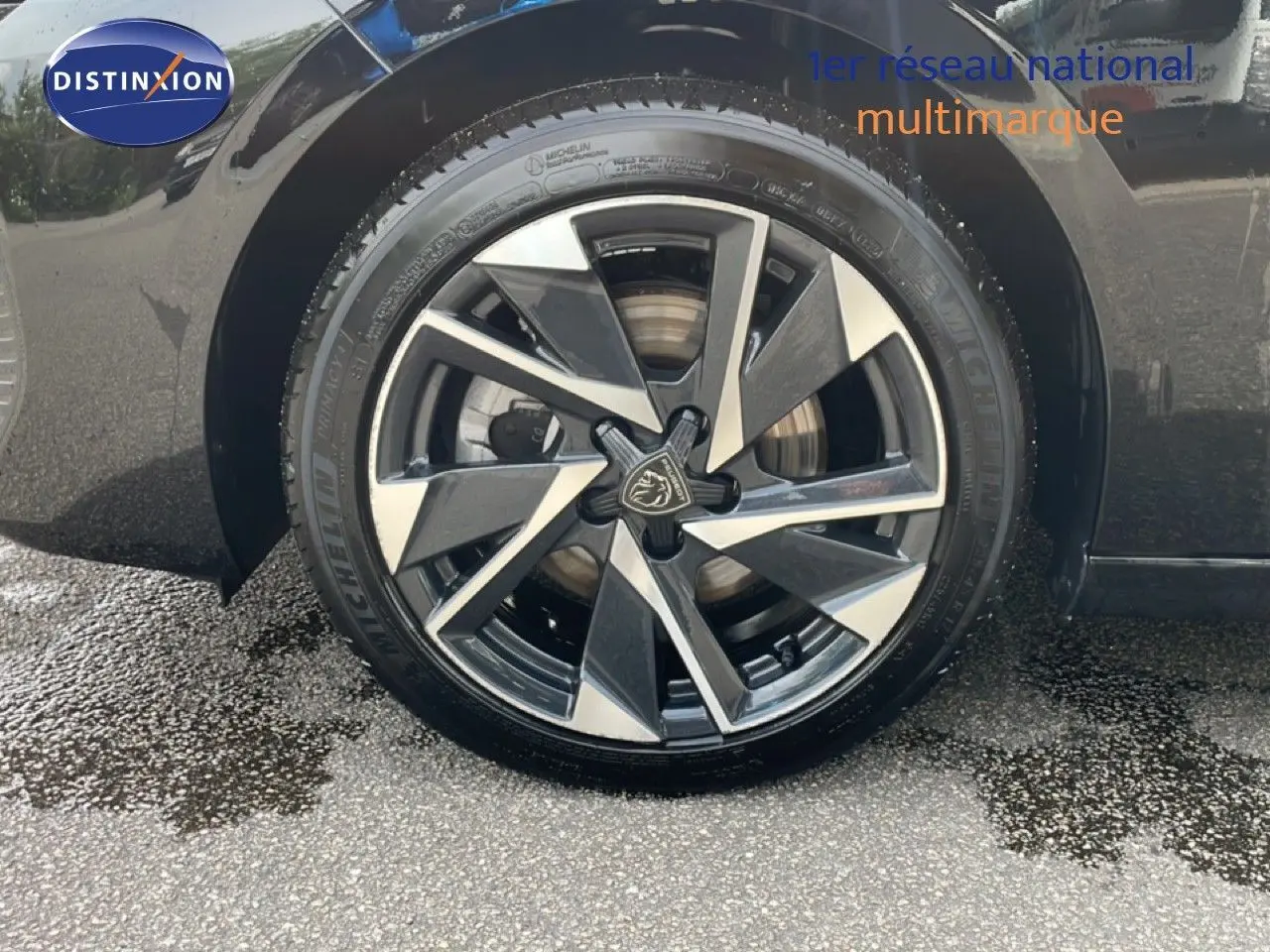 Gros plan sur la roue avant gauche noire métal d'une Peugeot 308 SW Hybrid 2025 avec jante alliage bicolore.