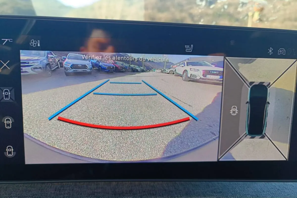 Affichage caméra de recul et vue 360° du Peugeot 3008 Hybrid 2025 avec repères de stationnement et environnement extérieur.