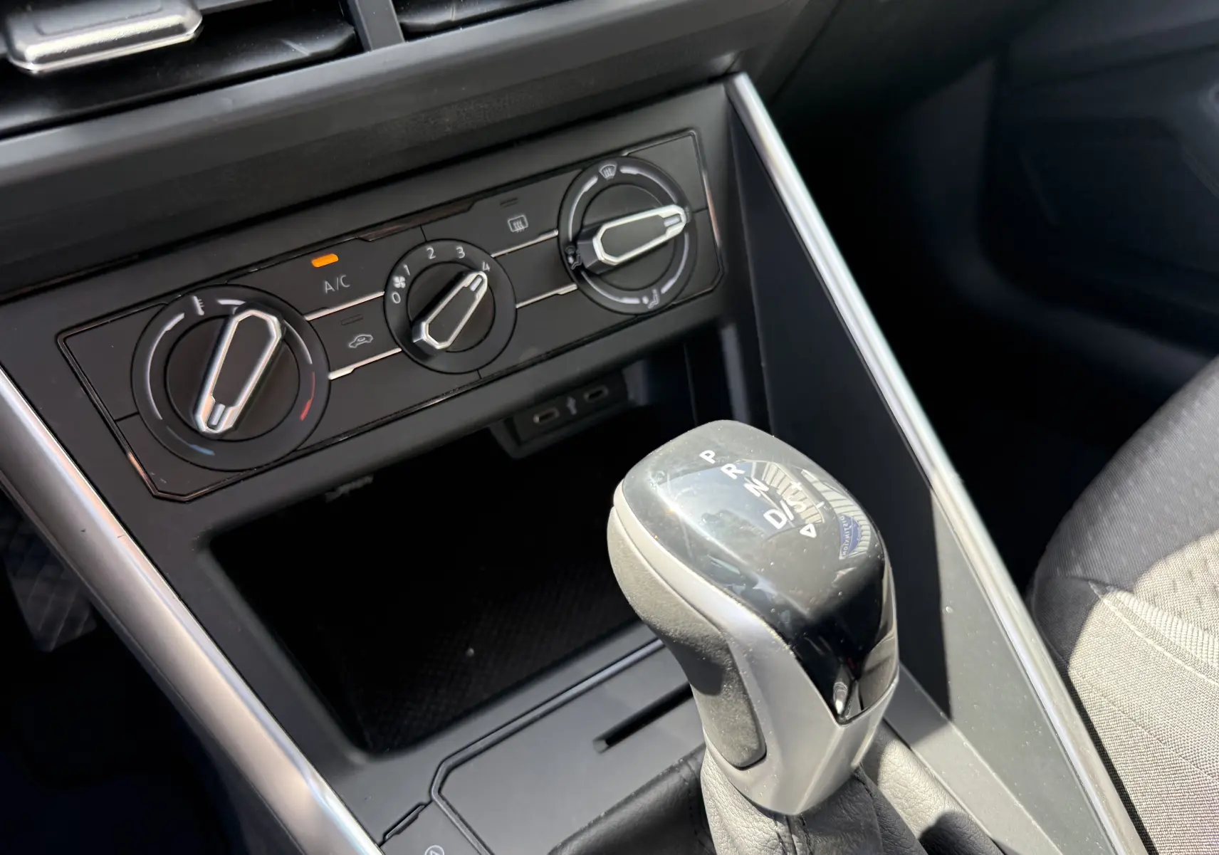 Gros plan sur la console centrale du Volkswagen Taigo 2022, montrant le levier de boîte auto et les commandes de climatisation.