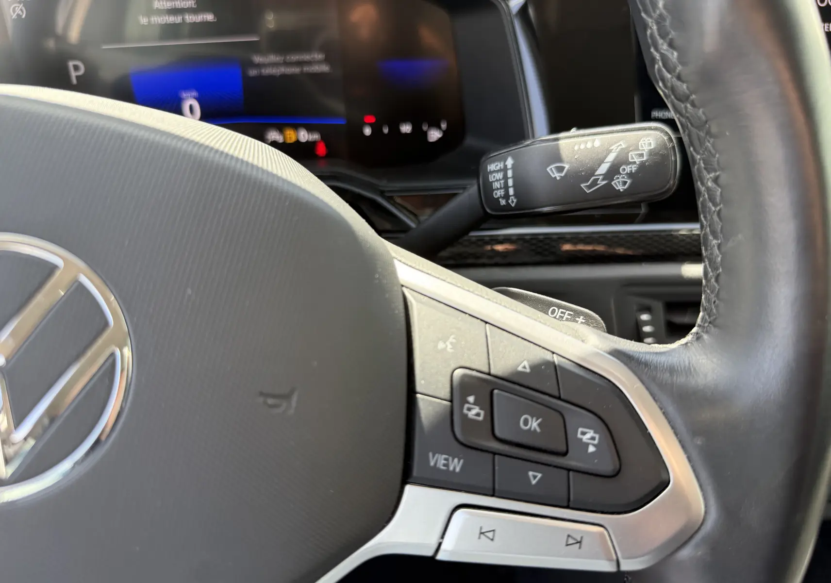 Gros plan sur le volant cuir noir du Volkswagen Taigo 2022 avec commandes intégrées et tableau de bord numérique en arrière-plan.