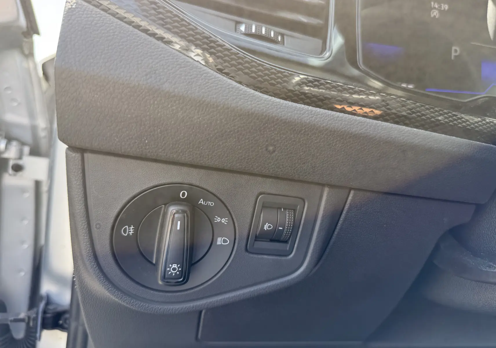 Gros plan sur le panneau de commande des phares à gauche du tableau de bord du Volkswagen Taigo gris reflet d'argent.