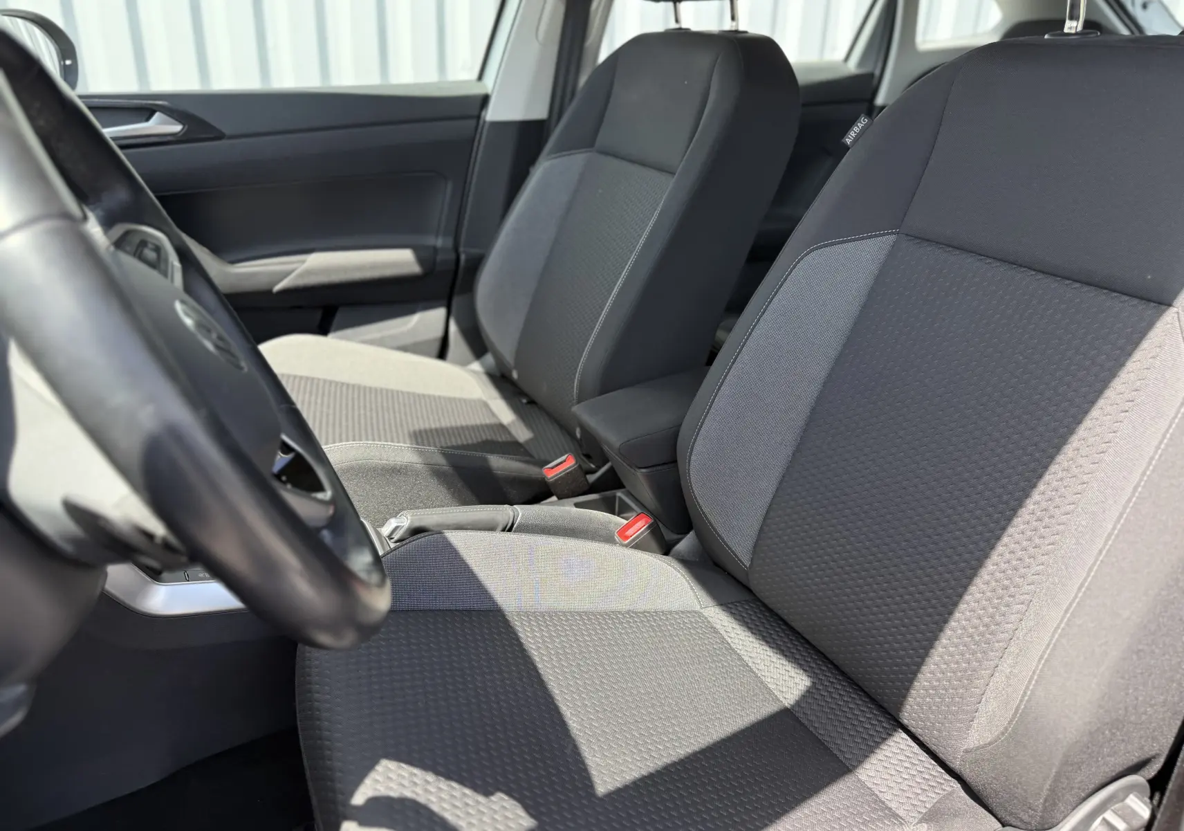 Vue rapprochée des sièges avant en tissu gris foncé du Volkswagen Taigo 2022, intérieur sobre et lumineux.