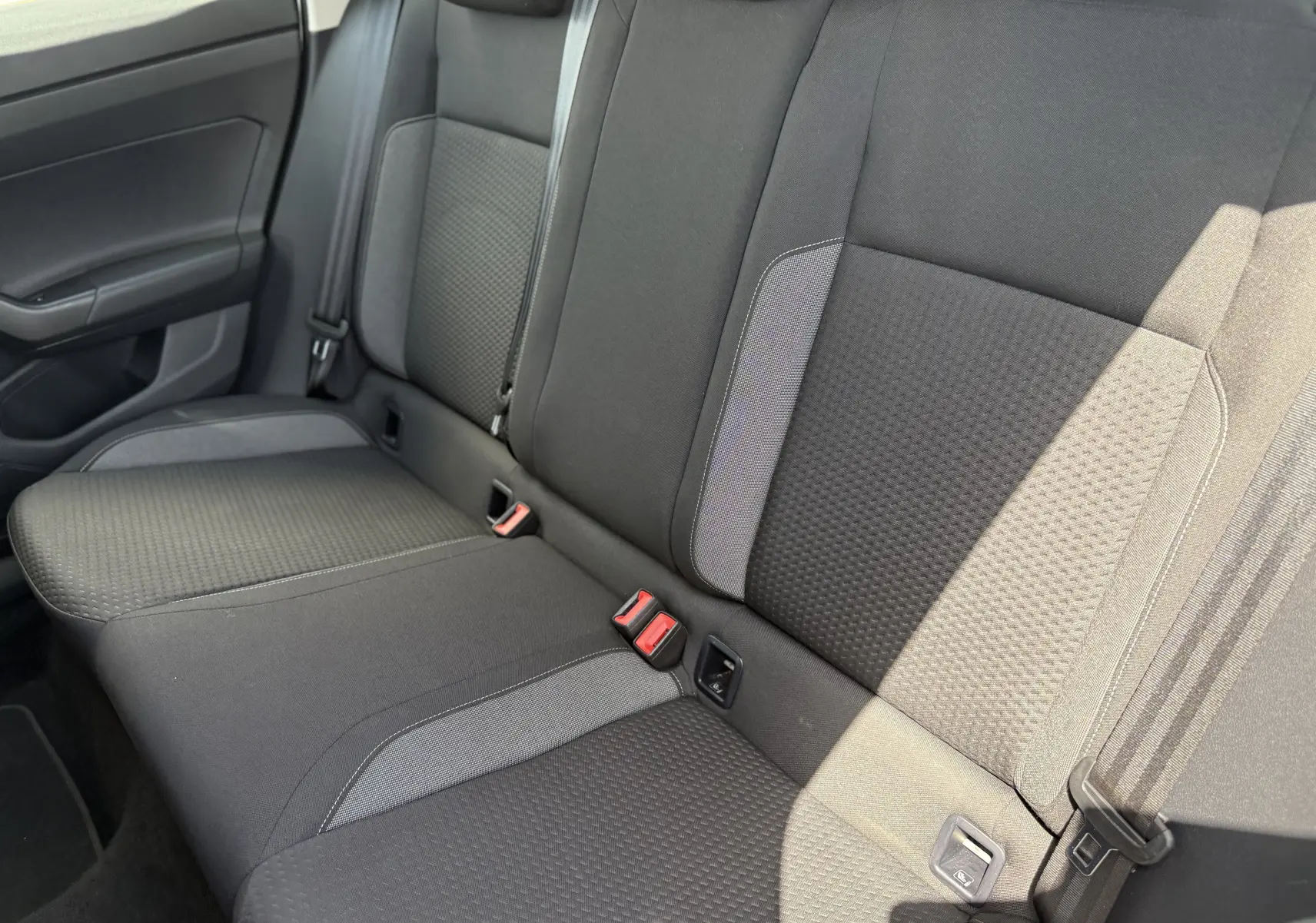 Vue intérieure des sièges arrière en tissu noir et gris du Volkswagen Taigo 2022, montrant les ceintures et ancrages ISOFIX.