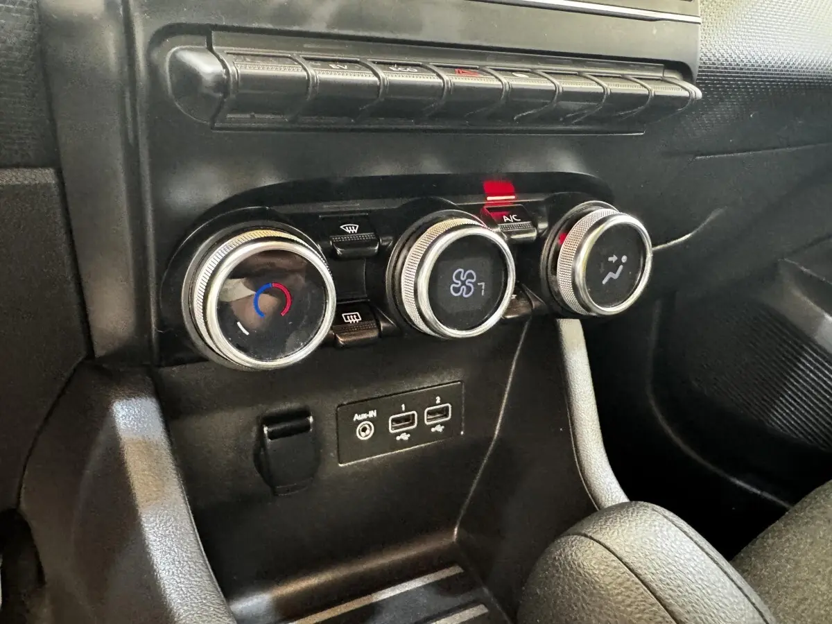 Gros plan sur les commandes de climatisation et les ports USB de la Renault Clio Business E-TECH gris clair.