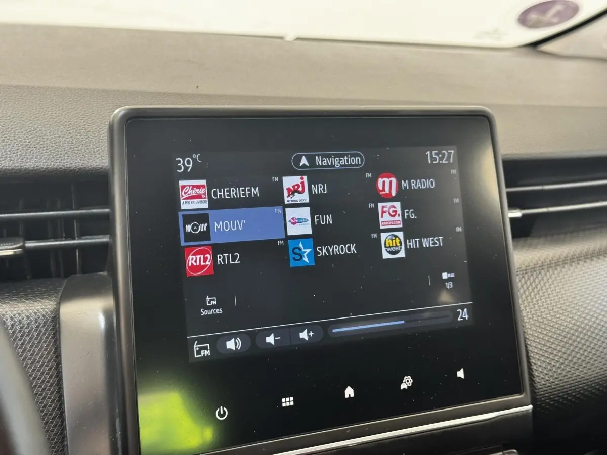Écran tactile central de la Renault Clio Business E-TECH 140 gris clair, affichant les stations radio FM.
