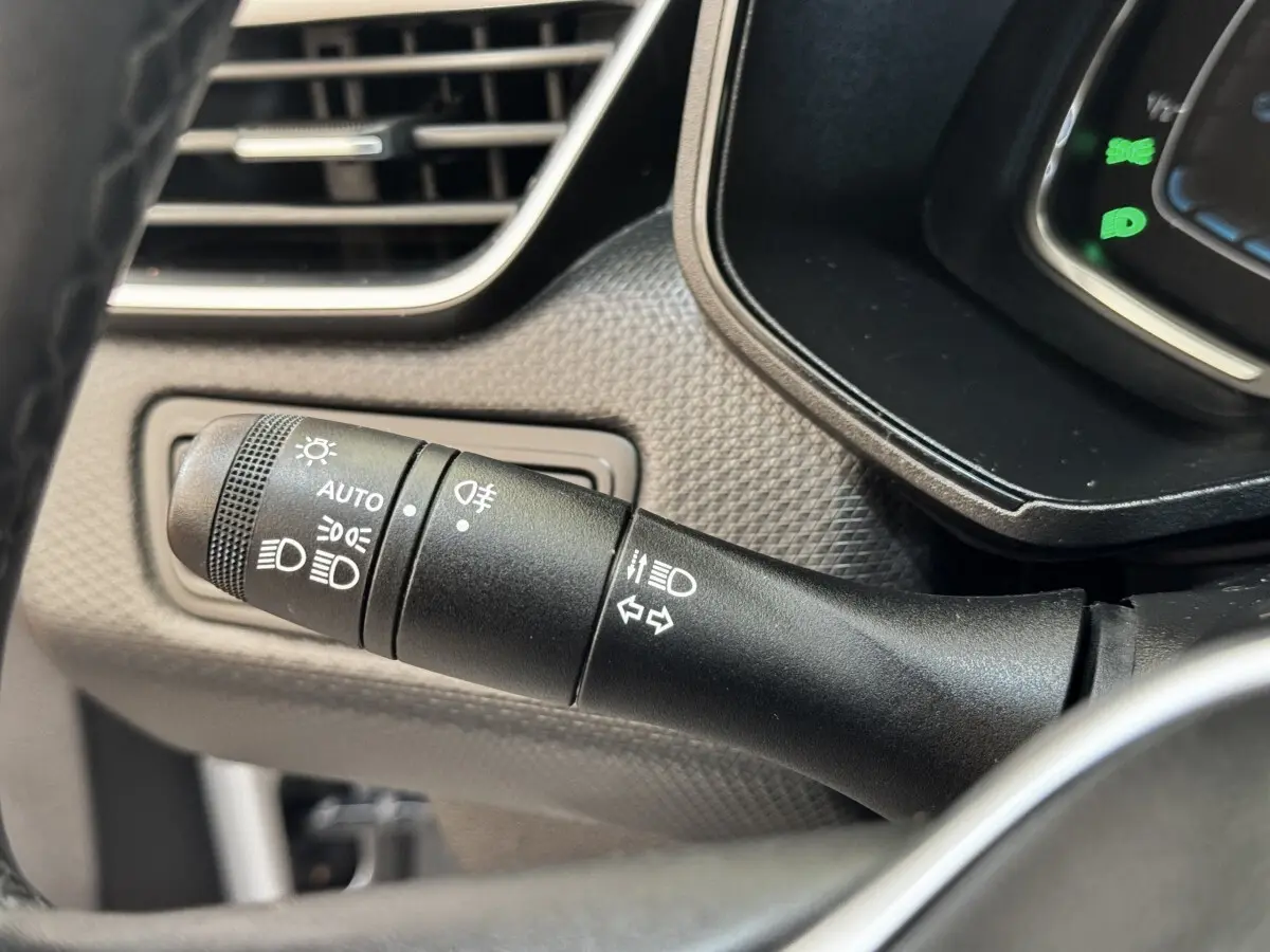 Gros plan sur la commande des phares et clignotants à gauche du volant dans une Renault Clio Business E-TECH 140 gris clair.