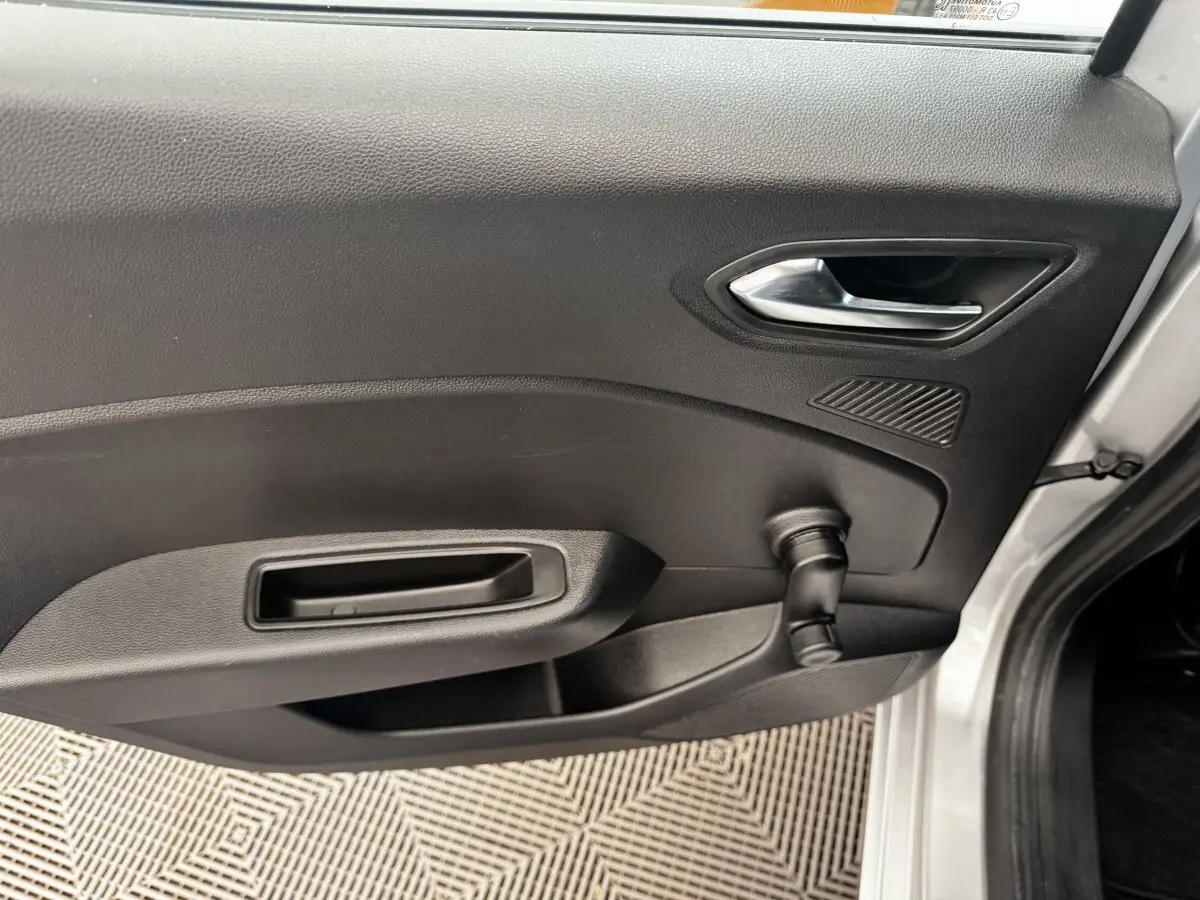 Vue intérieure côté gauche de la porte avant d'une Renault Clio Business E-TECH 140 gris clair avec poignée et manivelle de vitre.