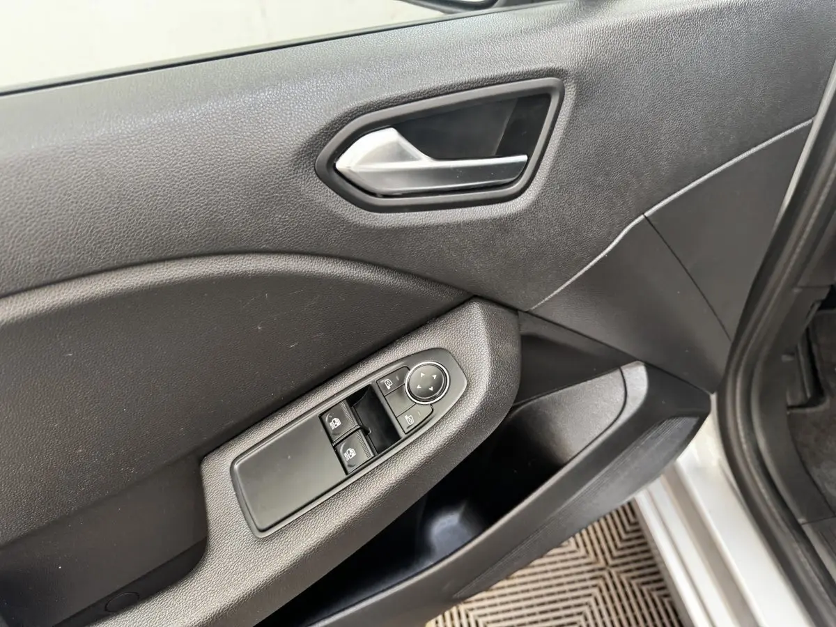 Détail de la porte avant droite grise de Renault Clio Business E-TECH 140 avec commandes électriques des vitres et rétroviseurs.