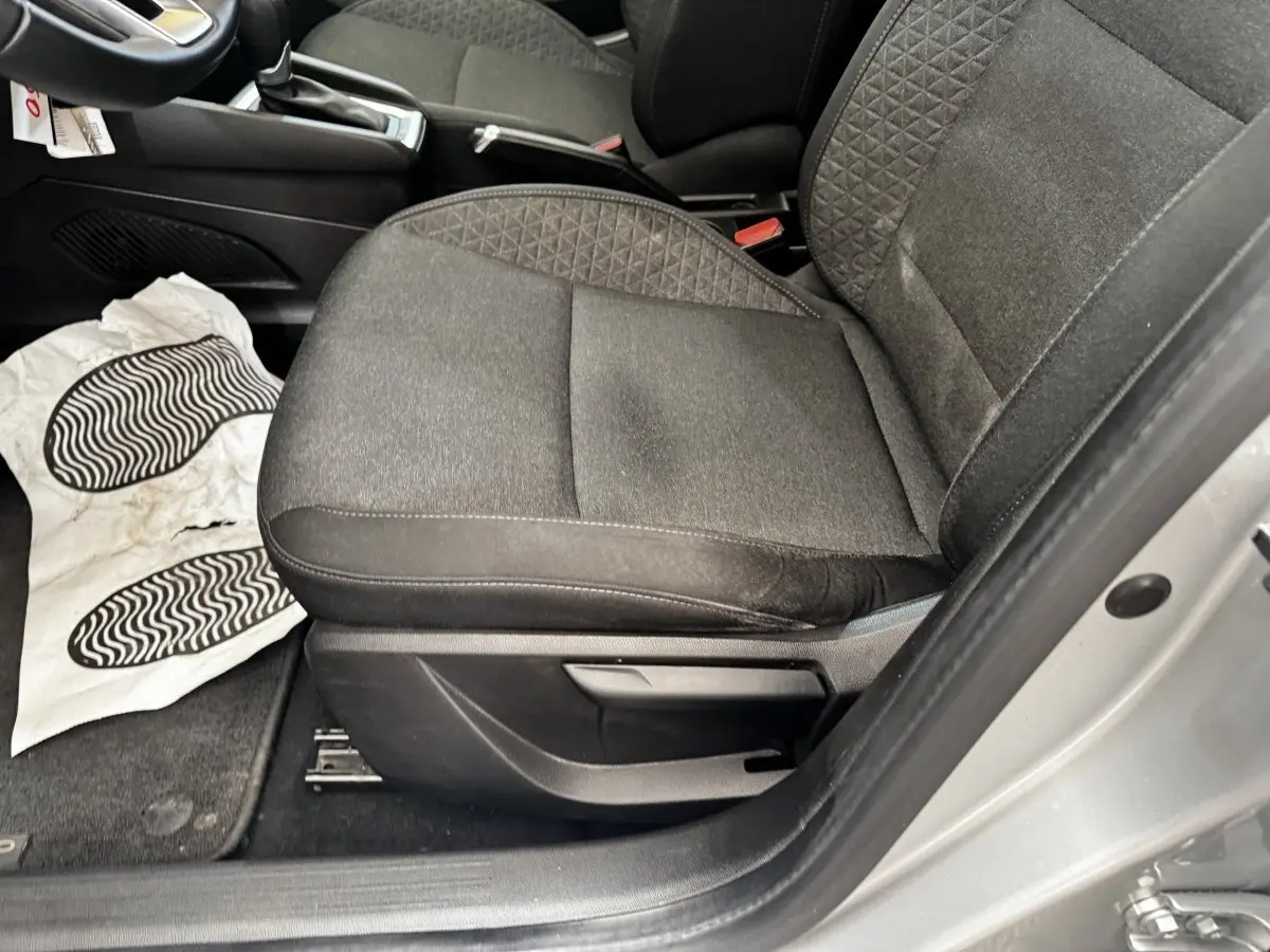 Vue rapprochée du siège avant droit en tissu noir de la Renault Clio Business E-TECH gris clair, porte ouverte.